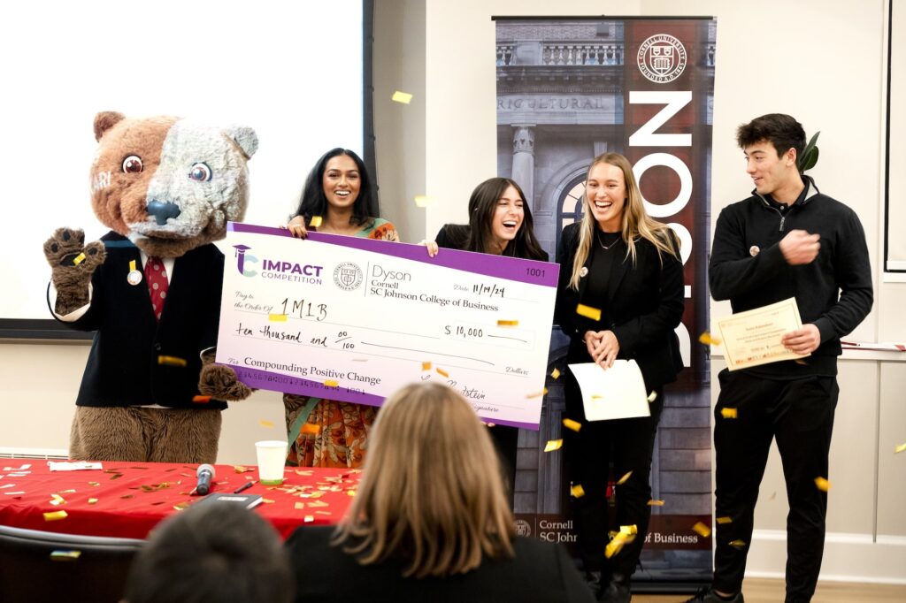 Happy team smiling holding check for $10,000
