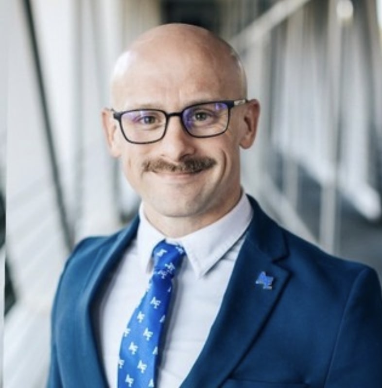 Seth Dunn headshot, smiling wearing suit and tie